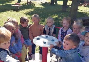 Dzieci siedzą na czerwonej karuzeli.