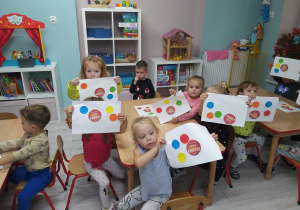 Grupka dzieci prezentuje swoje prace z kolorowymi kropkami.