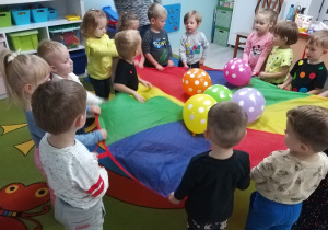 Dzieci delikatnie kołyszą balony umieszczone na chuście.