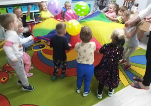 Wszystkie dzieci radośnie bawią się podrzucając balony na chuście.