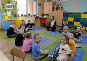 Dzieci siedzą na dywanie z panią Angeliką i rozmawiają na temat wysłuchanej bajki o dziewczynce Vashti.