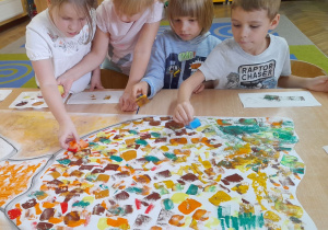 Hubert, Alicja, Maksymilian i Alicja siedzą przy wspólnym stole. Dzieci stempują z użyciem gąbek i farb w jesiennych kolorach.