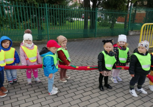 Dzieci stoją przy przejściu dla pieszych i obserwują ruch drogowy.