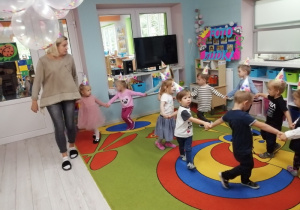Zabawa taneczna przy muzyce. Nauczyciel prowadzi "węża" - dzieci trzymają się za ręce, a na głowach mają papierowe czapeczki.