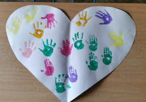 Wspólna praca plastyczna "Nasze serduszko" - ozdobione serce z kartonu kolorowymi odciskami dłoni dzieci.