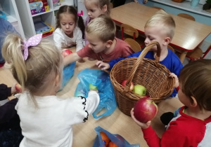 Dzieci wkładają zakupione jabłka do kosza.