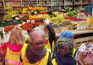 Biedronki oglądają asortyment sklepu owocowo - warzywnego.