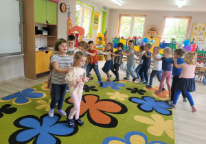 Dzieci z grupy Biedronek ustawione w węża tańczą przy muzyce.