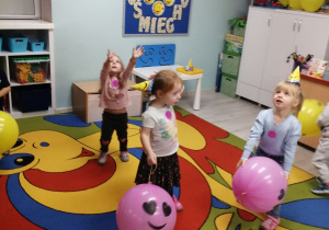 Swobodna zabawa przy muzyce na dywanie z kolorowymi balonami.