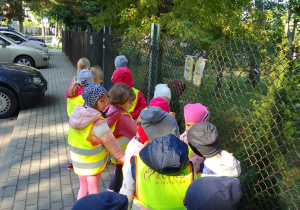 Dzieci idą chodnikiem w stronę pobliskiego skrzyżowania.