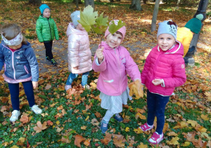 Dzieci spacerują po parku i zbierają „dary jesieni”.
