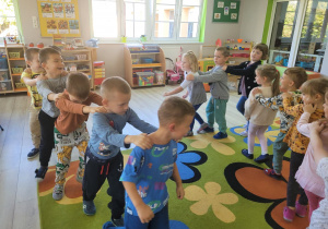 Dzieci z grupy Biedronek ustawione w pociąg w trakcie tańca przy muzyce.