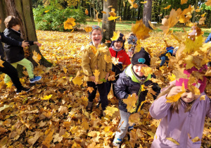 Dzieci z grupy w trakcie zabaw z liśćmi w pobliskim parku.