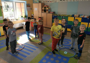 Dzieci z grupy Słoneczka w trakcie zabawy stoją na dywanie przy krążkach z określoną cyfrą.