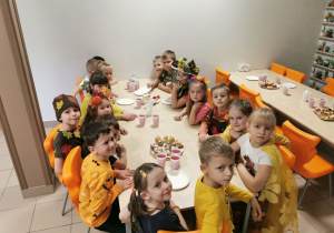 "Słoneczka" podczas przerwy siedzą przy stoliku i zaczynają jeść słodki poczęstunek.