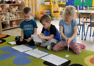 Franek, Eryk i Lena siedzą na dywanie i układają obrazek pod dyktando.