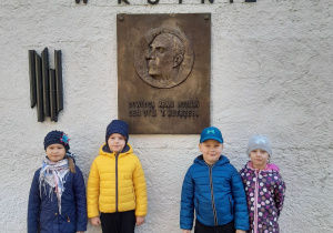 Czworo dzieci stoi przed tablicą upamiętniającą generała Tadeusza Kutrzebę. Nad tablicą, na murze znajduje się napis - Muzeum Bitwy nad Bzurą w Kutnie.