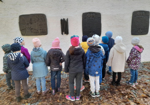 Dzieci oglądają tablice pamiątkowe umieszczone na "Murze pamięci" przed budynkiem Muzeum Bitwy nad Bzurą.