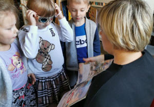 Oliwia w specjalnych okularach ogląda książkę z dinozaurami.