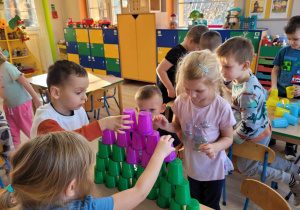 Dzieci z grupy Biedronek układają na stoliczkach kolorowe wieże z kubeczków