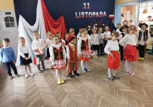 Dzieci z grupy "Słoneczek" i "Biedronek" w trakcie występu. W tle widać dekorację z napisem "11 listopada".