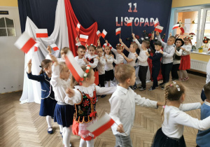 Dzieci z grupy "Słoneczek" tworzą pociąg, w ręku trzymają flagi biało-czerwone, którymi machają.