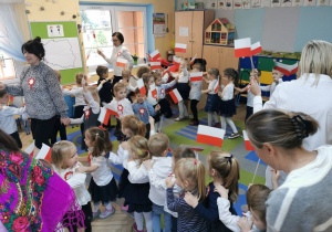 Dzieci z grupy "Pszczółek" i "Motylków" tworzą pociąg na dywanie do piosenki "Jestem Polakiem". W rękach trzymają papierowe biało-czerwone flagi.