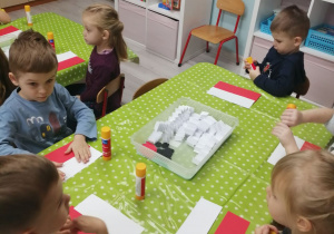 Grupka dzieci przy stoliku układa flagę Polski.