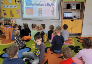 Biedronki siedząc na dywanie oglądają prezentację multimedialną.