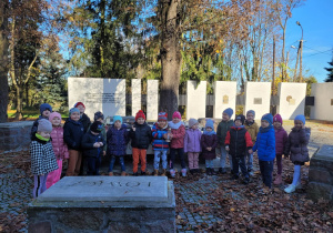 Dzieci z grupy Biedronek stoją wokół pomnika żołnierzy poległych w Bitwie pod Kutnem.