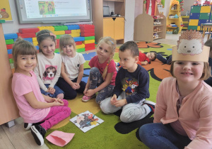 Dzieci z grupy "Biedronek" siedzą na dywanie i prezentują ułożony z części obrazek z wizerunkiem jeża.