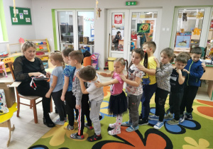 Dzieci z grupy "Słoneczka" ustawieni w pociągu przed panią Agnieszką czekają na otrzymanie upominków w ramach akcji "Bezpieczny przejazd".