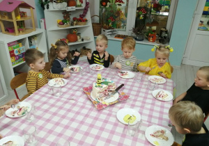 Dzieci siedzą przy stoliku i degustują tort.