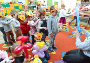 Dzieci ustawione w "pociąg" oczekują na balony o różnych kształtach.