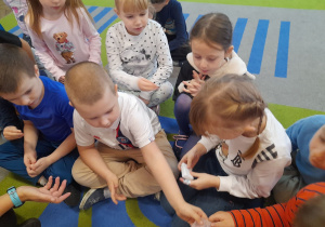 Dzieci siedzą na dywanie i oglądają bazę glicerynową.