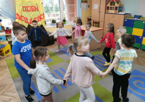 Dzieci z grupy "Słoneczka" tworzą koło trzymając się za ręce i śpiewają piosenkę "Grzeczne słówka".