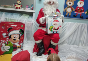 Mikołaj pokazuje zapakowane prezenty.