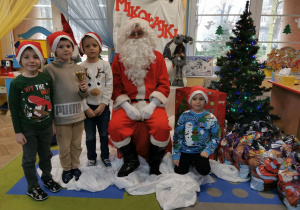 Oliwier, Krzysio, Hubert T. i Hubert K. pozują do zdjęcia ze Świętym Mikołajem.