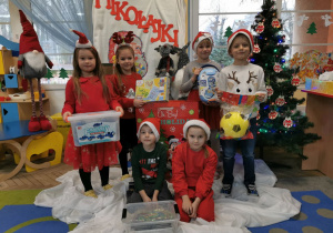 Grupka dzieci z grupy "Słoneczek" prezentuje prezenty od Świętego Mikołaja.