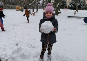 Vanessa stoi na śniegu i pokazuje dość dużą kulę, którą ulepiła.