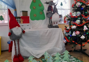 Świąteczna dekoracja, a pod nią wykonane przez dzieci prace - "świąteczne dywany i choinki".