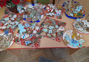 Na biurku leżą na talerzykach i świątecznych serwetkach kolorowe pierniki ozdobione przez rodziców i dzieci.
