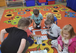 Dzieci z grupy Biedronek w trakcie rozkładania puzzli na dywanie