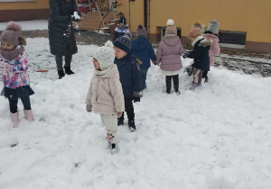 Grupka maluchów bawi się na śniegu.