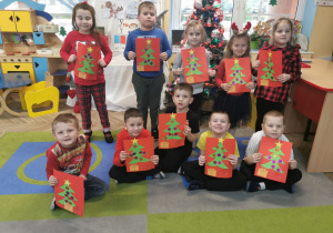 "Słoneczka" prezentują wykonany świąteczny obrazek według słownej instrukcji nauczyciela.