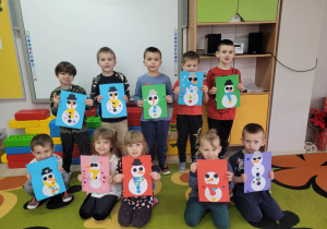 Dzieci z grupy Biedronek ustawione przy tablicy multimedialnej prezentują wykonane przez siebie prace