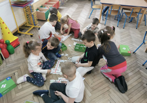 Dzieci z grupy "Biedronek" i "Słoneczek" w trakcie układania trasy/drogi z drewnianych puzzli.