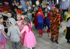 Dzieci tańczą na środku sali przy muzyce. W tle dekoracja balowa.