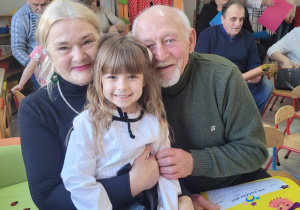Zosia z grupy Biedronek siedzi na kolanach swojej babci, obok siedzi dziadek Zosi.