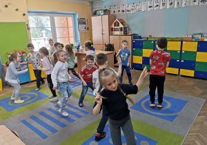 Dzieci z grupy "Słoneczka" tańczą na dywanie przy muzyce w trakcie zabawy ruchowej "Skocz ile razy usłyszysz".